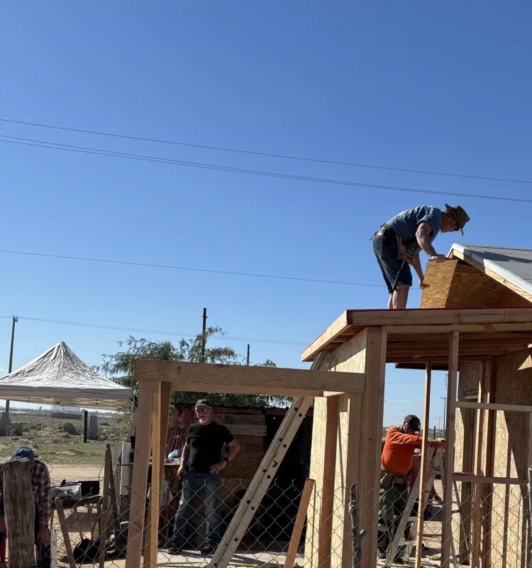 Volunteers framing and roofing a home under construction
