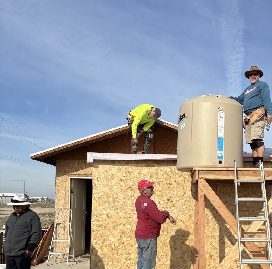 Volunteers installing a water tower on a roof